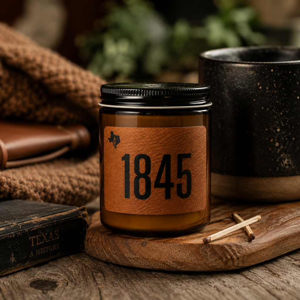 Candle with a leather label reading '1845' on a wooden surface with a book and mug in the background.