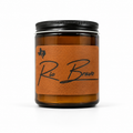 Rio Bravo 8oz soy candle in an amber glass jar with a black lid and a leather label with script lettering, on a white background.
