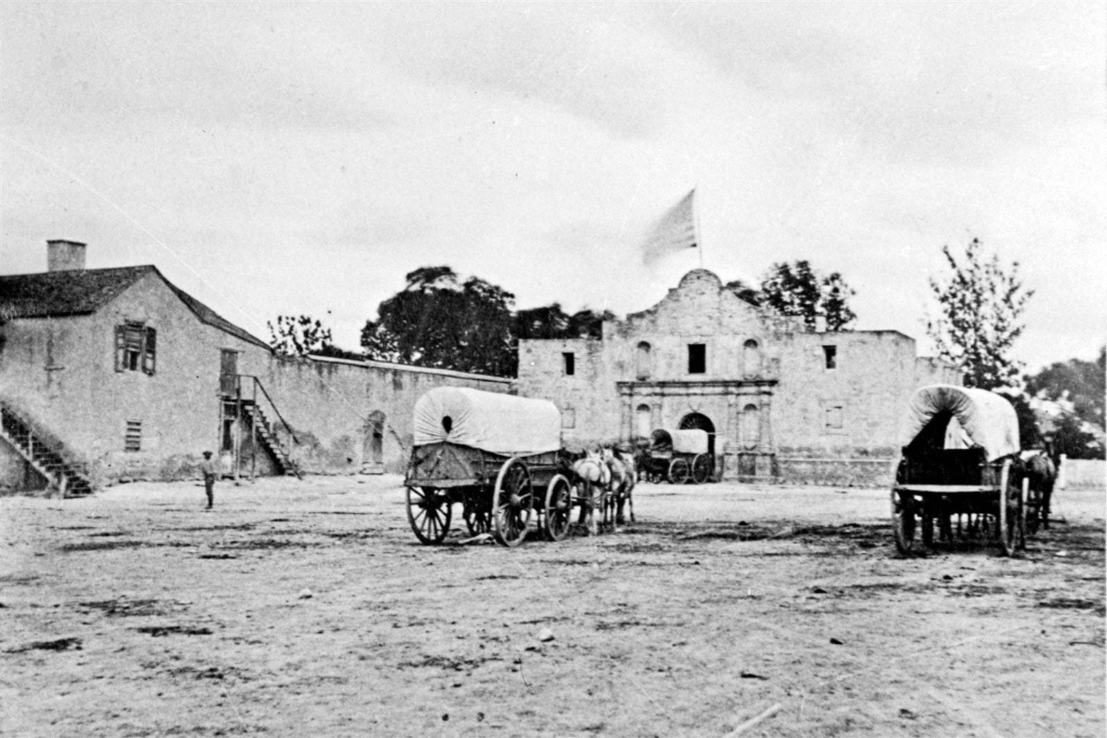 The Alamo in the 1800s with covered wagons in the plaza